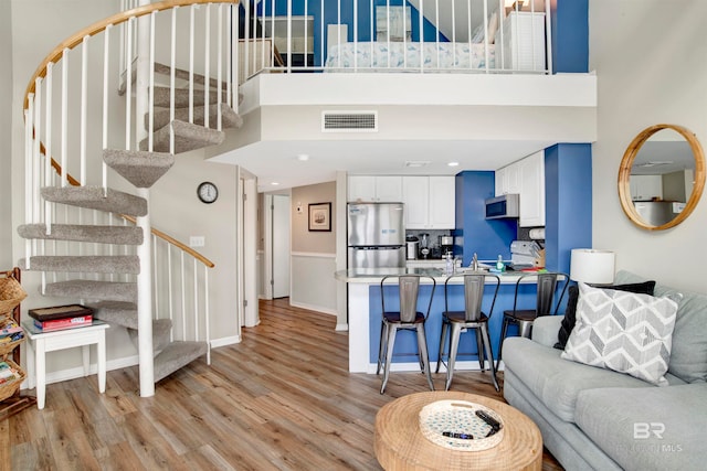 living room with a towering ceiling and light hardwood / wood-style floors