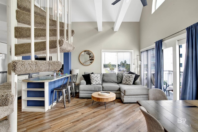 living area with light wood-style flooring, ceiling fan, beam ceiling, and high vaulted ceiling