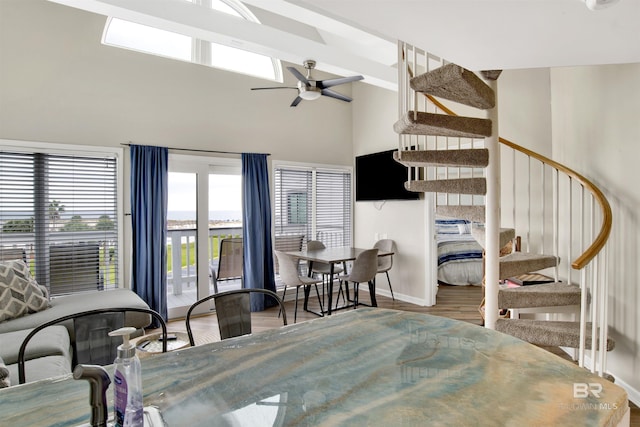 dining space featuring ceiling fan, high vaulted ceiling, baseboards, a wealth of natural light, and stairway