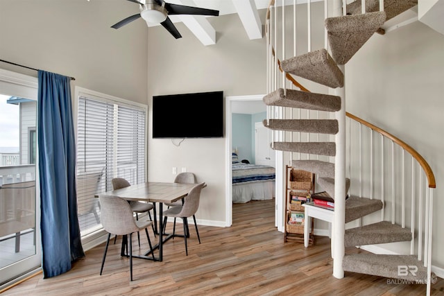 dining space featuring ceiling fan, hardwood / wood-style flooring, and a towering ceiling