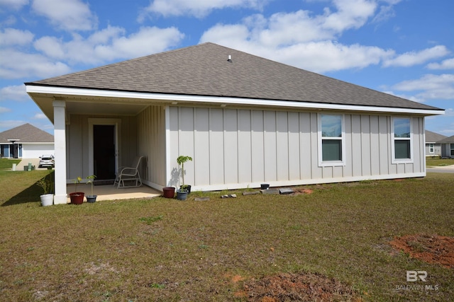 rear view of property featuring a lawn, board and batten siding, and a shingled roof