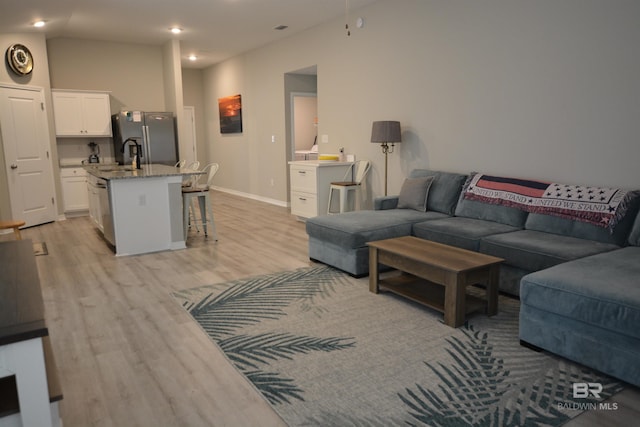 living room with recessed lighting, baseboards, and light wood-style floors