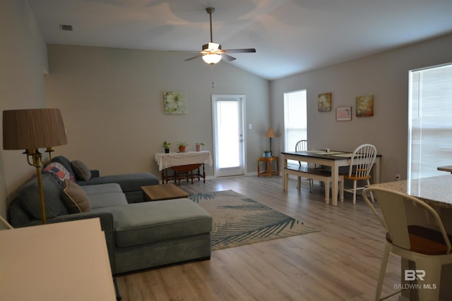 living room with visible vents, wood finished floors, a ceiling fan, and vaulted ceiling