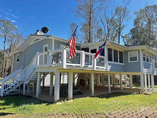 rear view of house with stairs, a patio, and a lawn