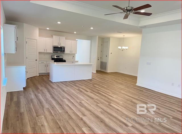 kitchen with appliances with stainless steel finishes, light wood-type flooring, ceiling fan with notable chandelier, a kitchen island with sink, and white cabinetry