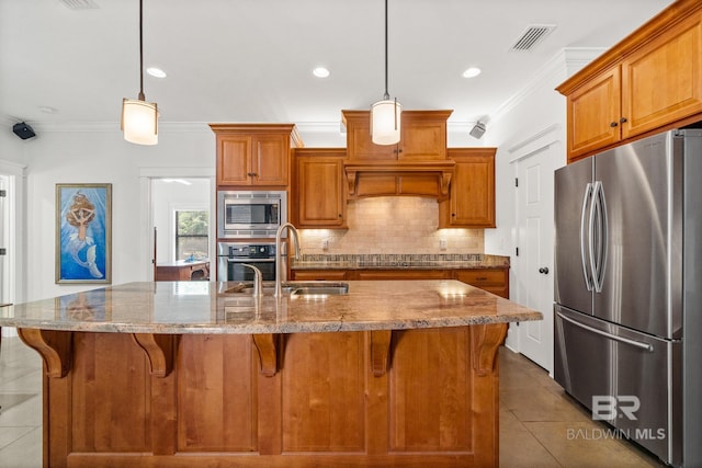 kitchen featuring an island with sink, stainless steel appliances, sink, and pendant lighting