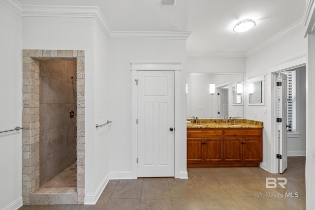 bathroom with a tile shower, ornamental molding, vanity, and tile patterned flooring