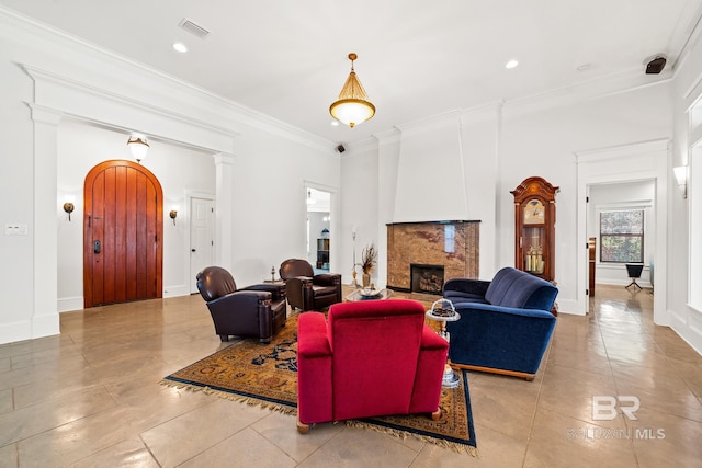 living room featuring ornate columns, a large fireplace, ornamental molding, and light tile patterned floors