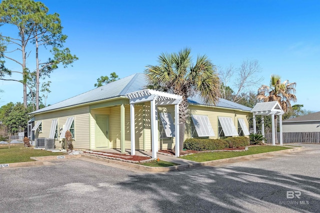 view of front facade featuring central air condition unit, a pergola, and metal roof