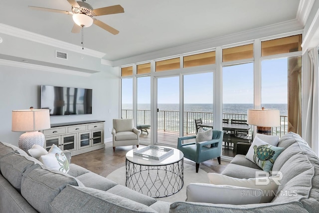 tiled living room featuring a wealth of natural light, ceiling fan, a water view, and ornamental molding