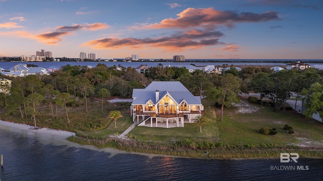 aerial view at dusk featuring a water view