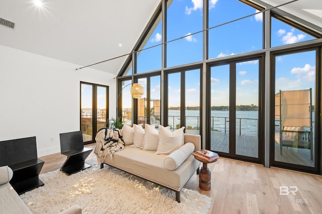 living room featuring plenty of natural light, a wall of windows, french doors, and a water view