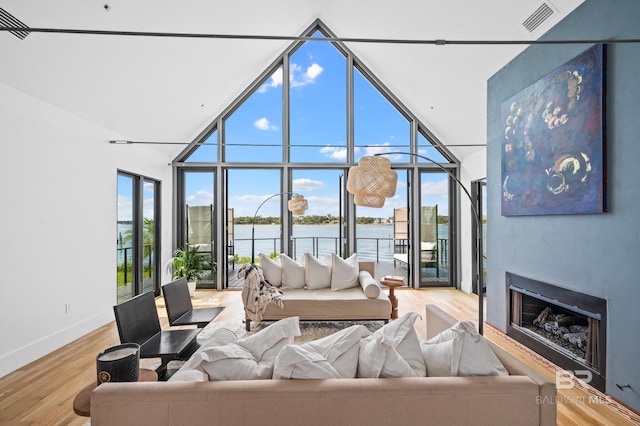 living room featuring hardwood / wood-style floors, high vaulted ceiling, and a water view