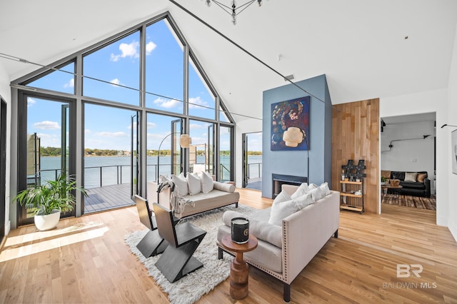 living room featuring high vaulted ceiling, a large fireplace, plenty of natural light, and a water view