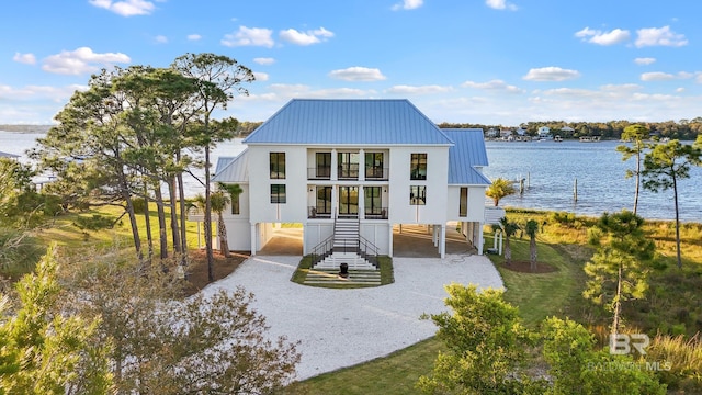 back of property with covered porch, a balcony, and a water view