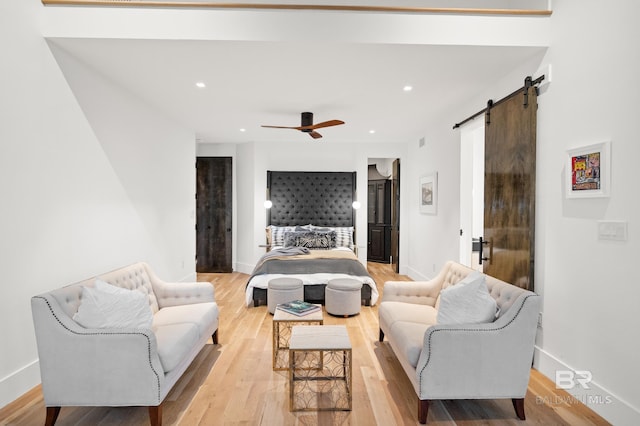 bedroom with ceiling fan, light hardwood / wood-style floors, and a barn door