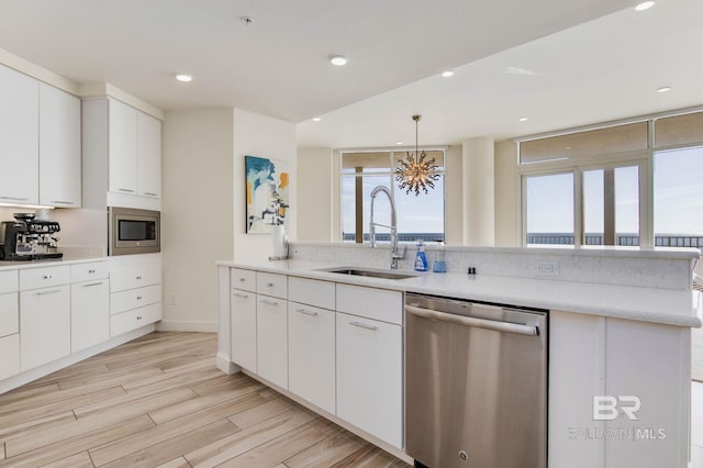 kitchen with light wood-type flooring, white cabinetry, appliances with stainless steel finishes, and sink