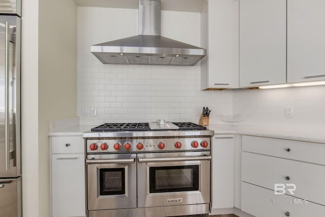 kitchen featuring white cabinetry, wall chimney range hood, stainless steel appliances, and tasteful backsplash