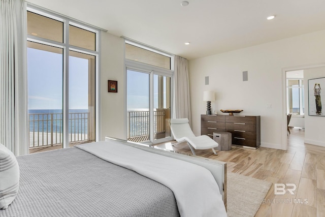 bedroom with light hardwood / wood-style flooring, a water view, and access to exterior