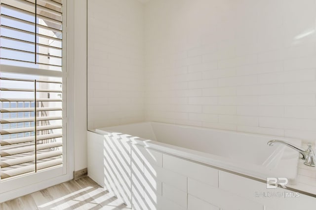 bathroom with tiled bath and hardwood / wood-style floors