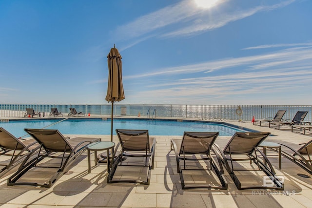 view of pool with a patio and a water view