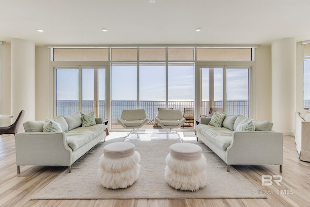 living room with a water view, light hardwood / wood-style floors, and expansive windows