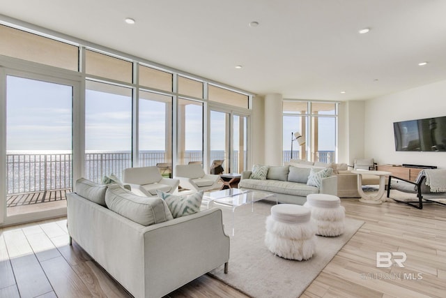 living room featuring light wood-type flooring and floor to ceiling windows