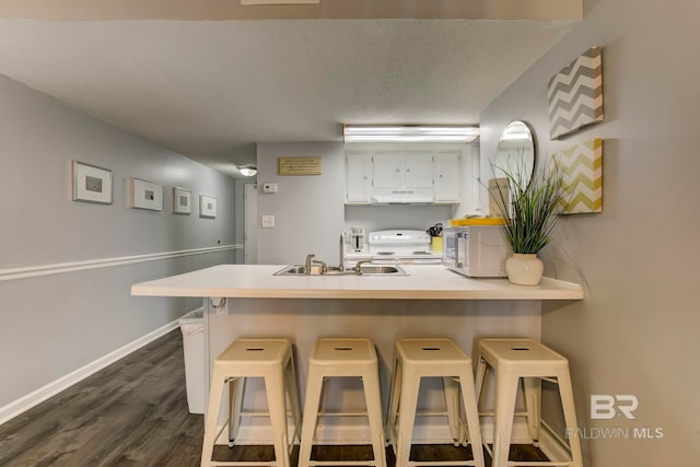 kitchen featuring a breakfast bar, dark hardwood / wood-style flooring, kitchen peninsula, and sink