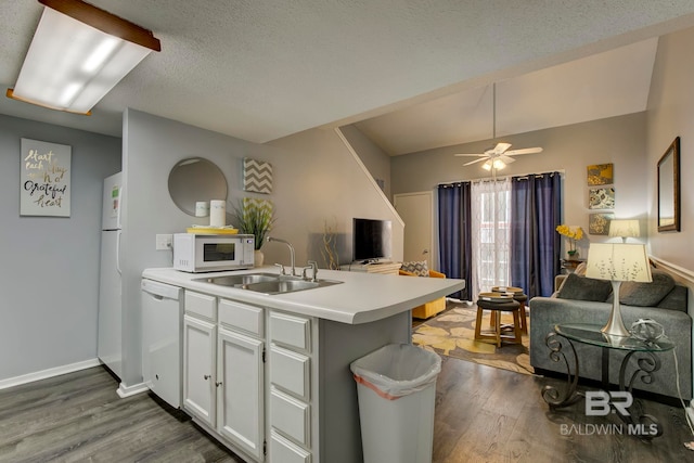 kitchen with white cabinetry, dark wood-type flooring, white appliances, kitchen peninsula, and sink