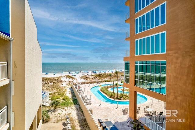 view of pool featuring a beach view, a patio, and a water view