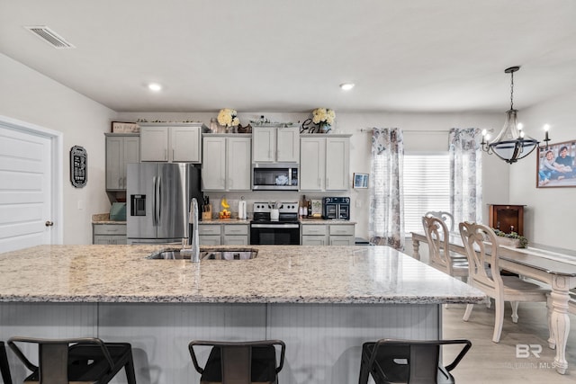 kitchen with stainless steel appliances, visible vents, a sink, and a kitchen bar