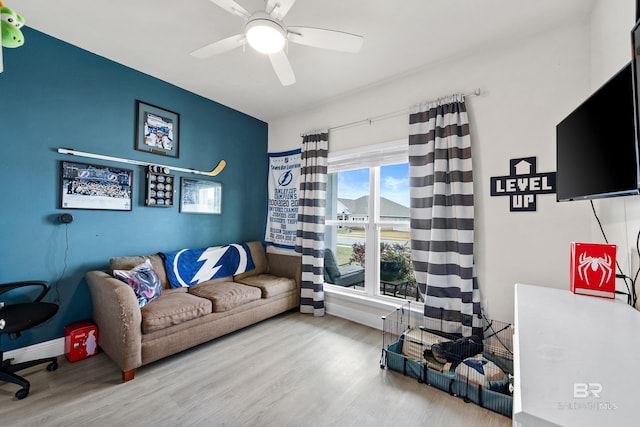 interior space featuring a ceiling fan, baseboards, and wood finished floors