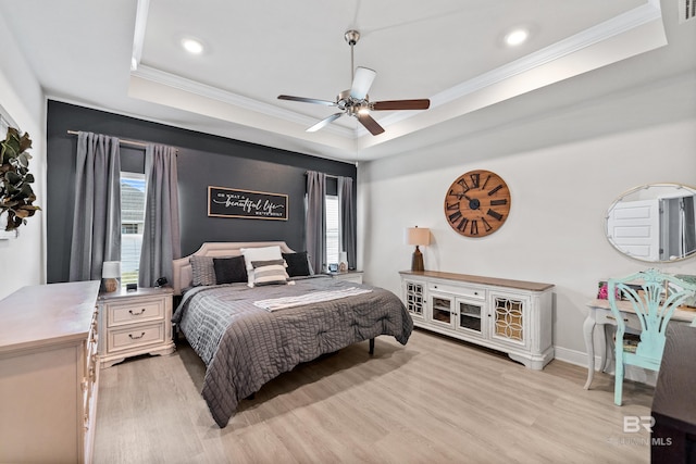 bedroom with light wood-style flooring, a raised ceiling, and crown molding