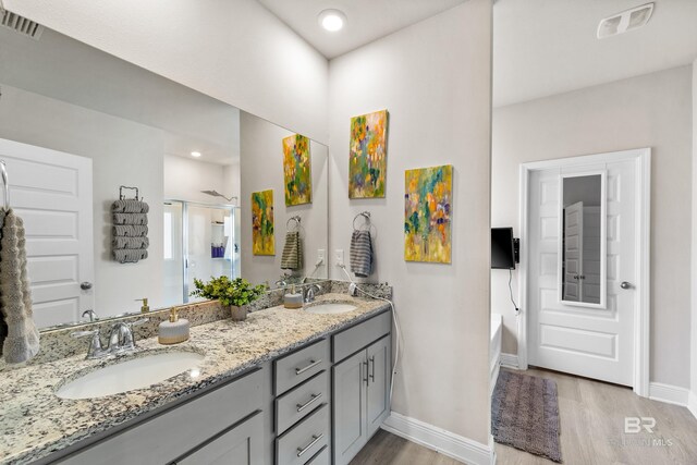 bathroom with wood finished floors, a sink, visible vents, and a shower stall