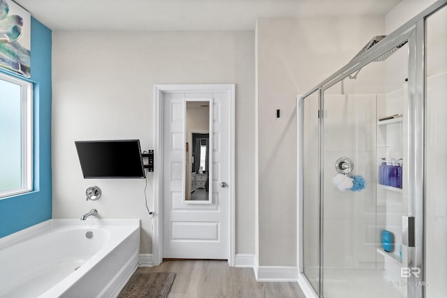 full bathroom featuring a garden tub, wood finished floors, a shower stall, and baseboards