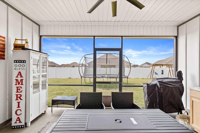 sunroom / solarium featuring a residential view and a ceiling fan