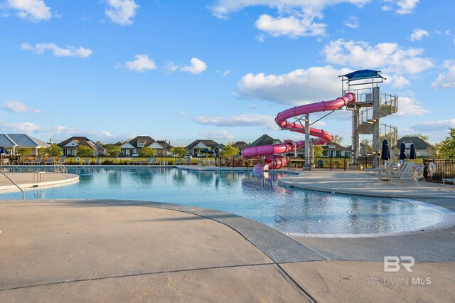 community pool with a water slide, a patio, and fence