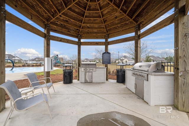 view of patio with a grill, fence, exterior kitchen, and a gazebo