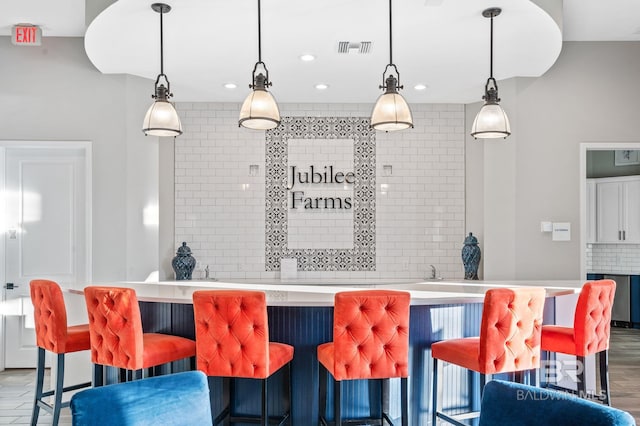 kitchen featuring tasteful backsplash, light countertops, wood finished floors, and decorative light fixtures