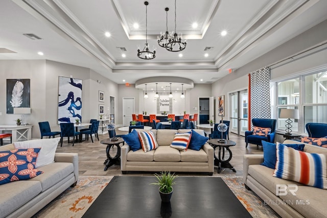 living room with light wood-style floors, visible vents, a tray ceiling, and ornamental molding