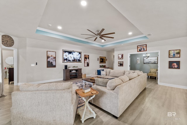 living area featuring a tray ceiling, visible vents, and light wood-style flooring