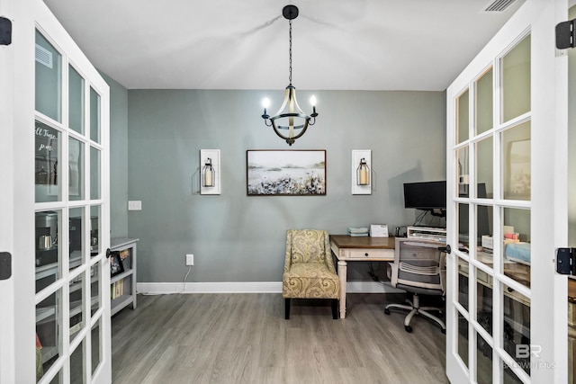 office featuring a notable chandelier, wood finished floors, visible vents, and baseboards