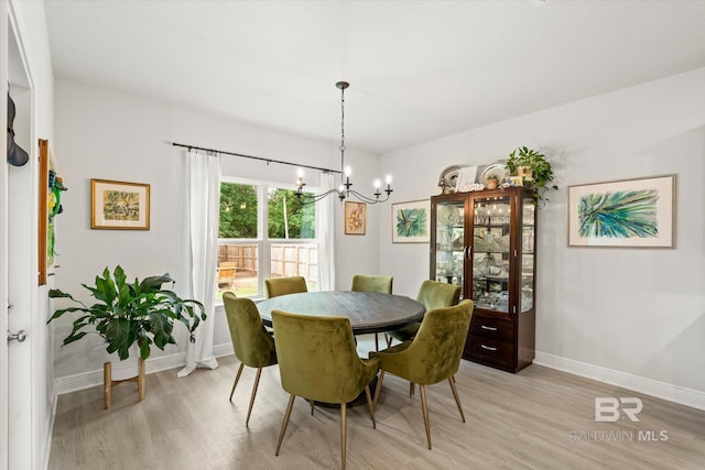 dining area featuring light wood finished floors, a chandelier, and baseboards