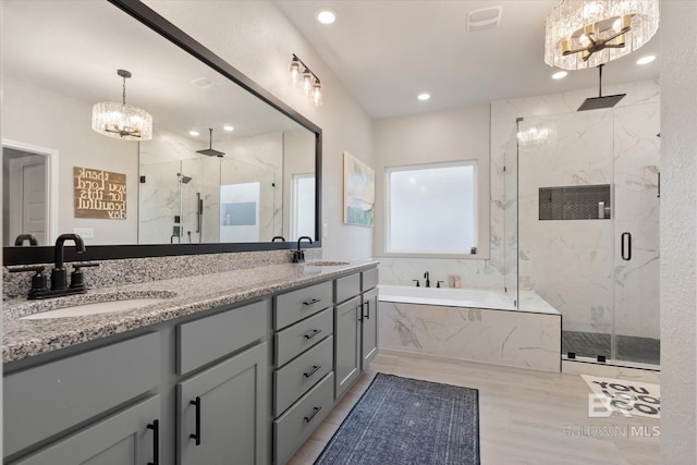 bathroom with a chandelier, a marble finish shower, a garden tub, double vanity, and recessed lighting