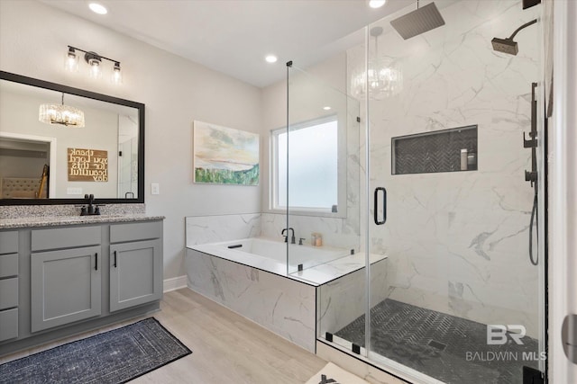 bathroom with a chandelier, a marble finish shower, a garden tub, and recessed lighting