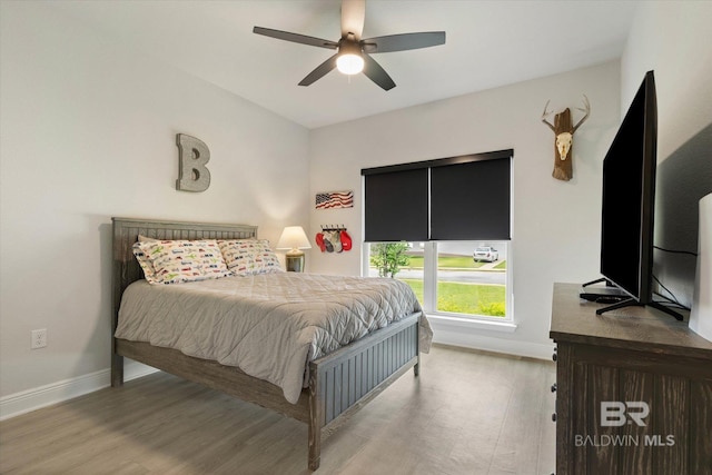 bedroom featuring baseboards, wood finished floors, and ceiling fan