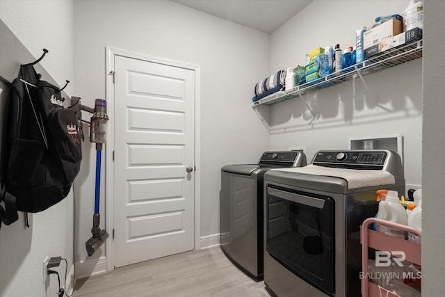 washroom with separate washer and dryer, light wood-style flooring, and baseboards