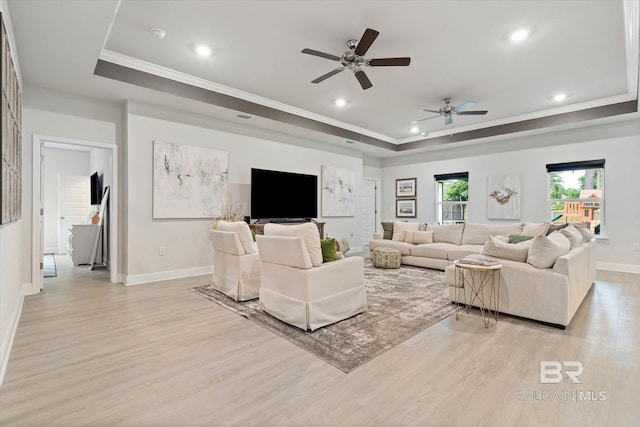 living room featuring a tray ceiling, crown molding, light wood-style floors, recessed lighting, and a ceiling fan