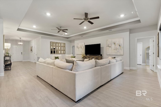 living room featuring a tray ceiling, baseboards, light wood-style flooring, a ceiling fan, and recessed lighting