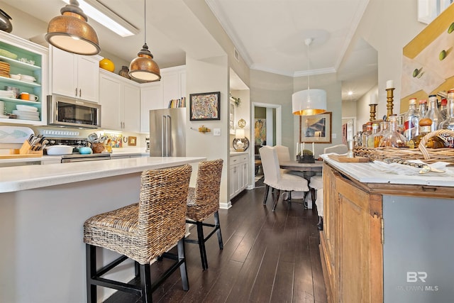 kitchen featuring hanging light fixtures, appliances with stainless steel finishes, dark hardwood / wood-style flooring, and white cabinets